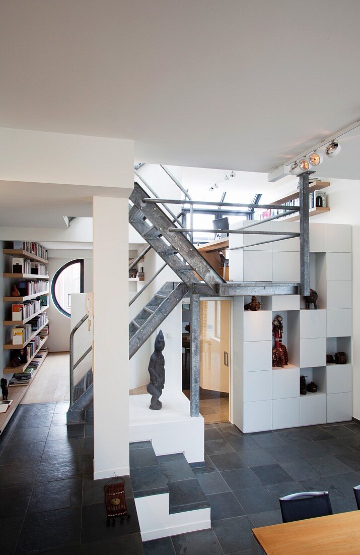 Verschachtelte Galerieebenen in einem Wohnraum mit puristischer, offener Metallgittertreppe
