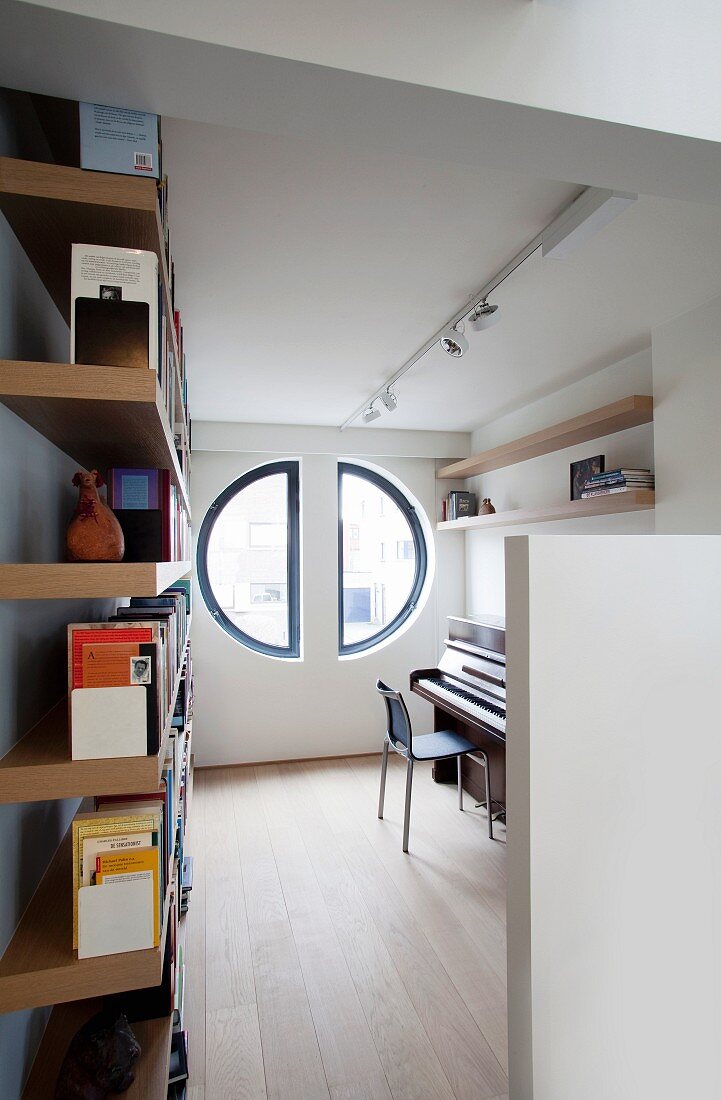 Two semicircular windows in study with bookcase and piano