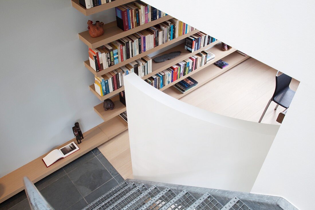 View down wire mesh stairs of floating bookshelves in study