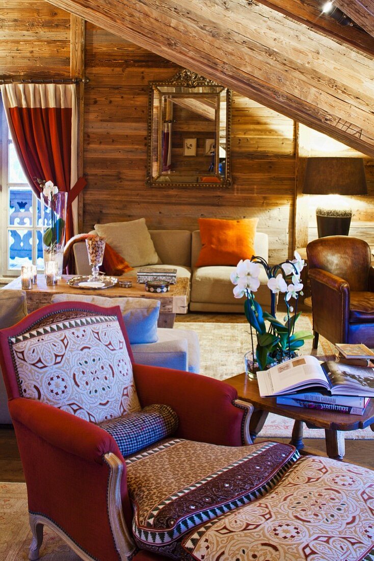 Sessel mit Fussschemel in gemütlichem Wohnzimmer einer Holzhütte