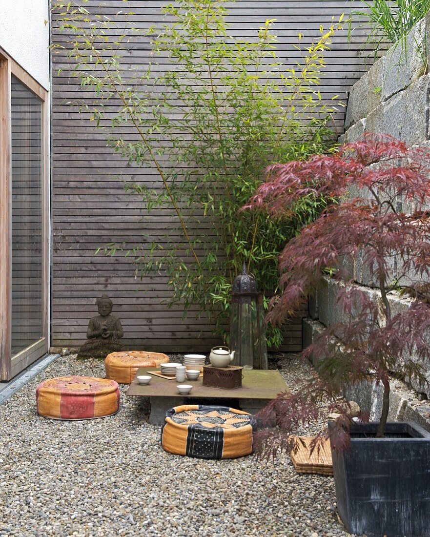 Contemporary Japanese-style courtyard - tea ceremony on improvised table and floor cushions on gravel floor