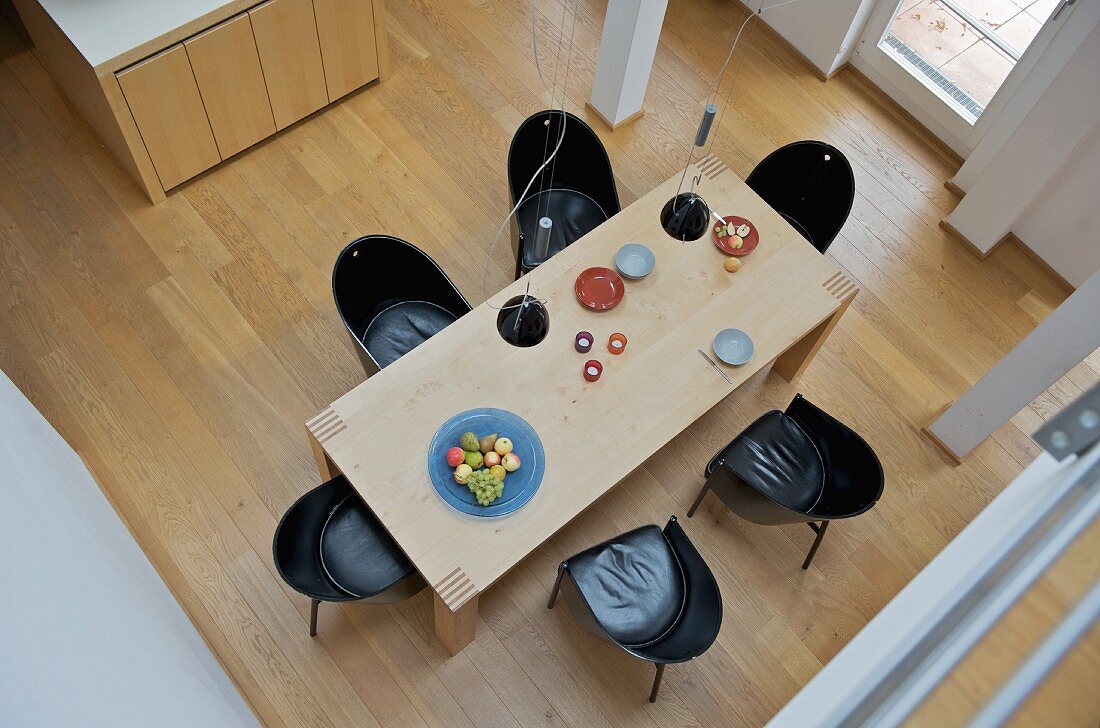Blick auf einen modernen Esstisch und schwarze Schalenstühle auf Holzboden
