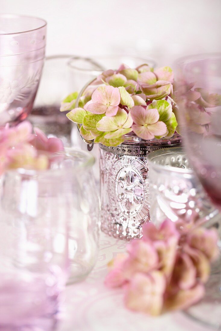Empty wine glasses and pink hydrangeas in silver beaker