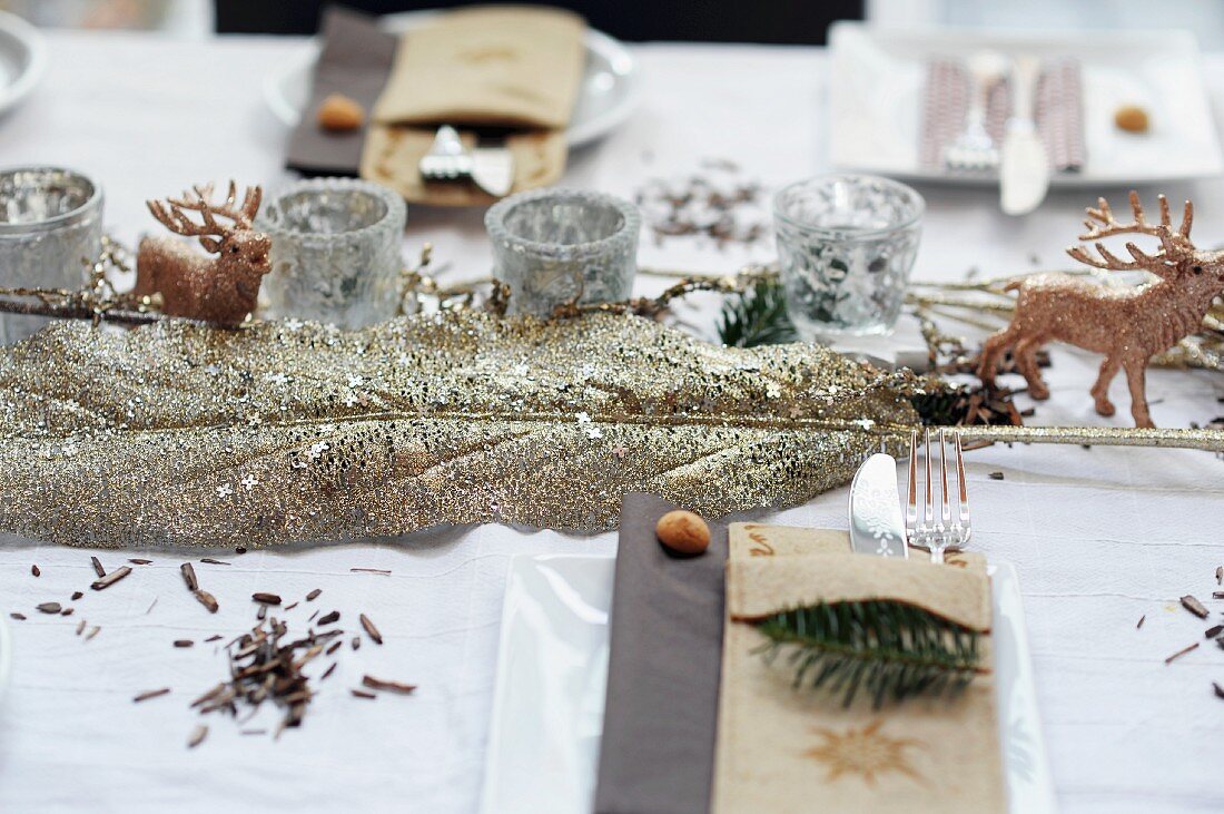Christmas table decorations: leaf covered in gold glitter, stag ornament and silver tealight holders