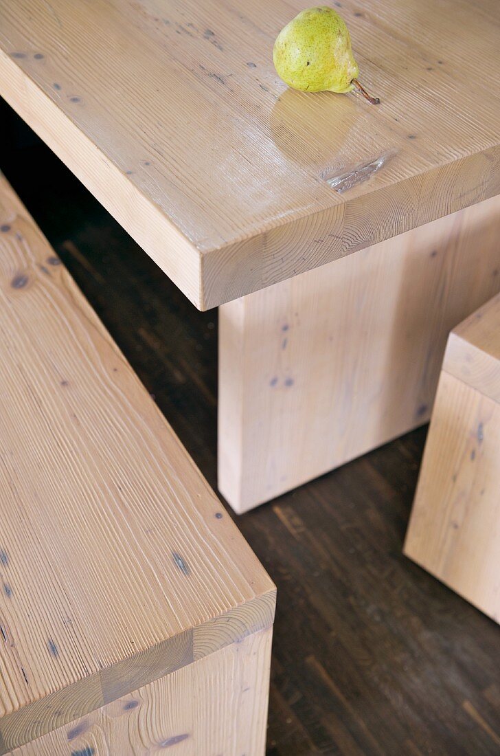 Pear lying on simple wooden table next to matching bench