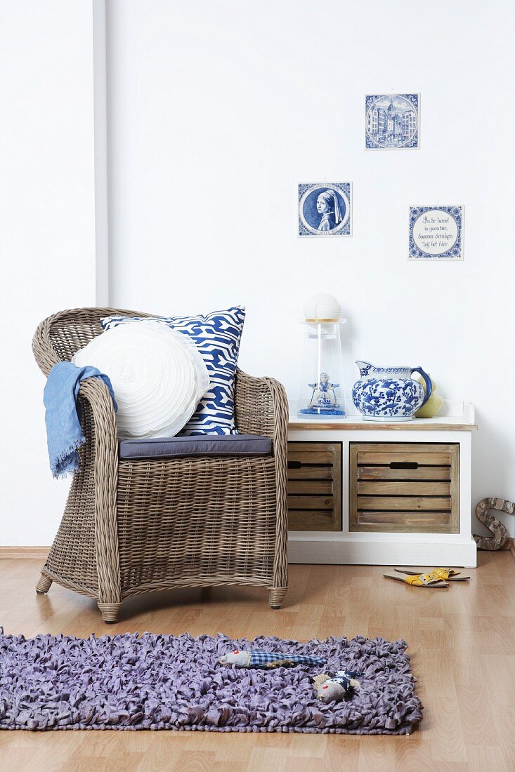 Wicker armchair in front of storage bench with Dutch ornaments and single wall tiles