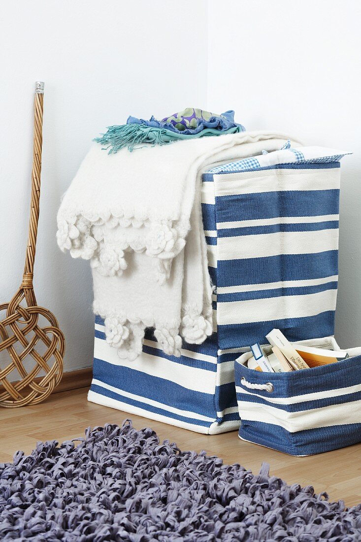 Blue and white laundry basket with lid and small storage basket with rug in foreground