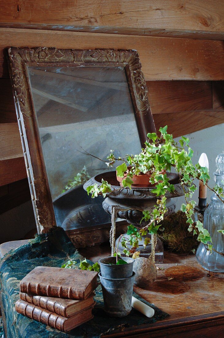Antike Sammlerfunde mit Patina und ein Efeupflanztopf in alter Amphore dekoriert auf einer Kommode