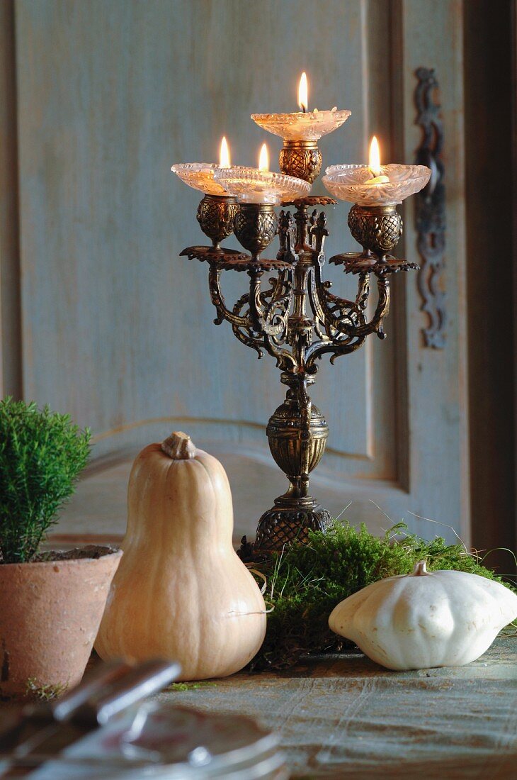 Antiker Kerzenleuchter im Rokokostil und kleine Kürbisse mit Moos-Dekoration