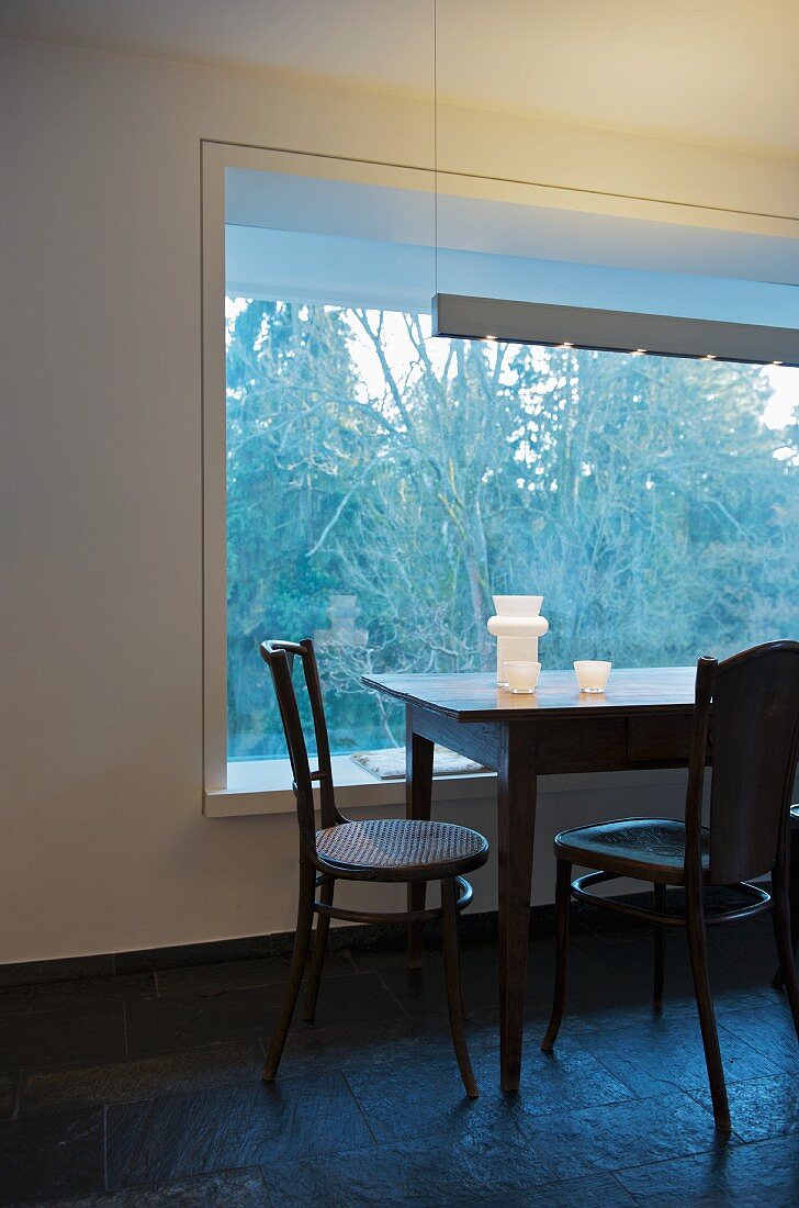 Schlichter Esstisch mit Stühlen vor festverglastem Fensterelement