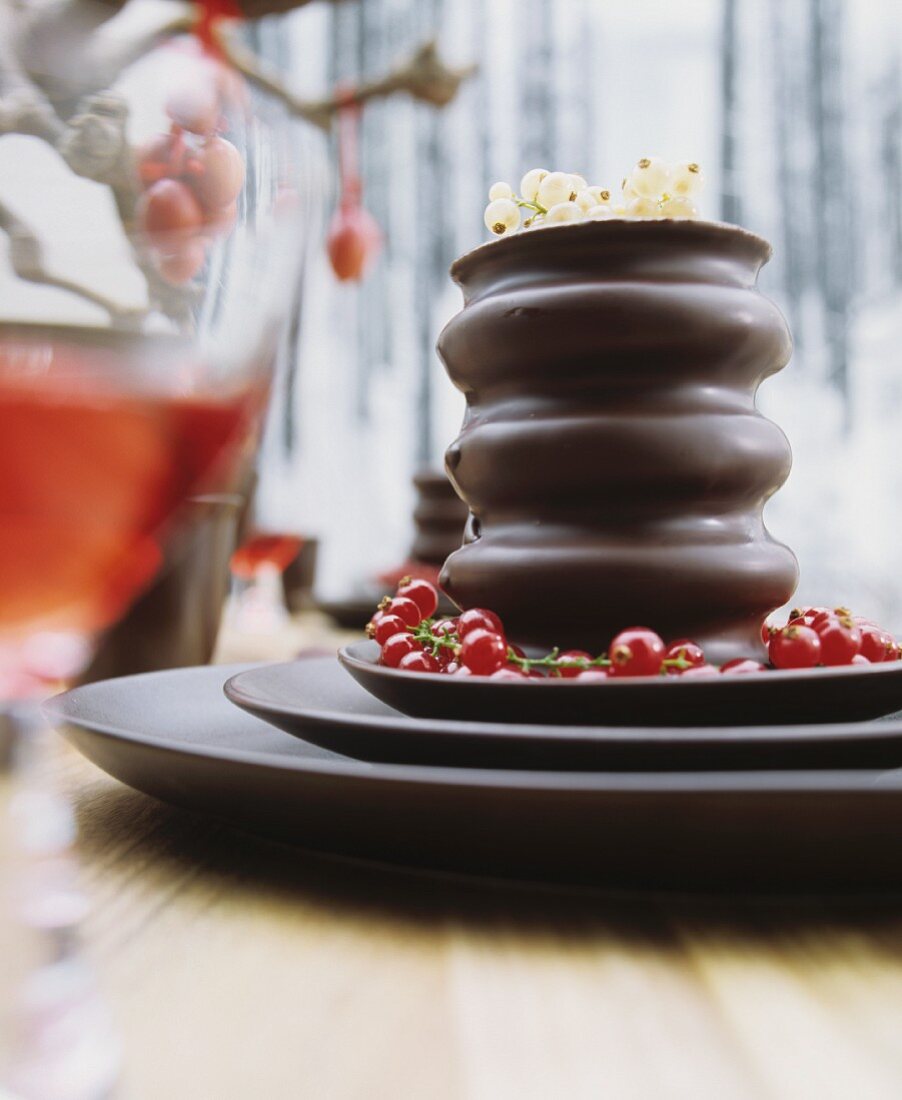 Baumkuchen (German layer cakes) with trusses of redcurrants on a set of dark brown ceramic dishes