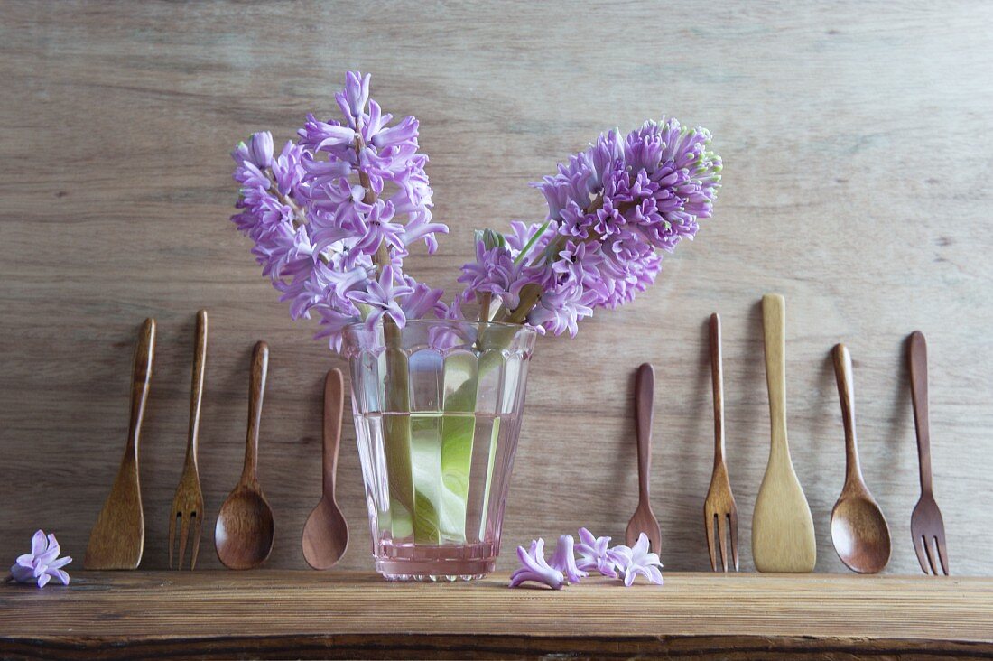 Hyacinths in glass of water and wooden utensils on shelf