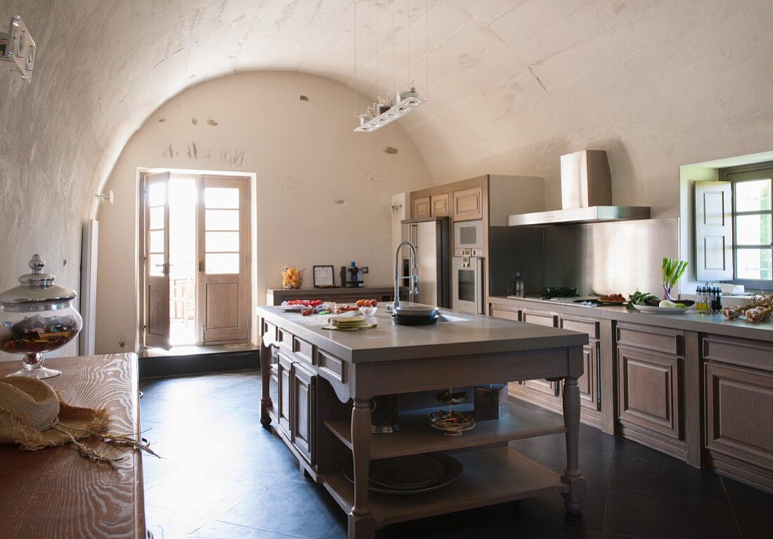 Traditional, simple kitchen with central island below barrel vaulted ceiling in Mediterranean country house