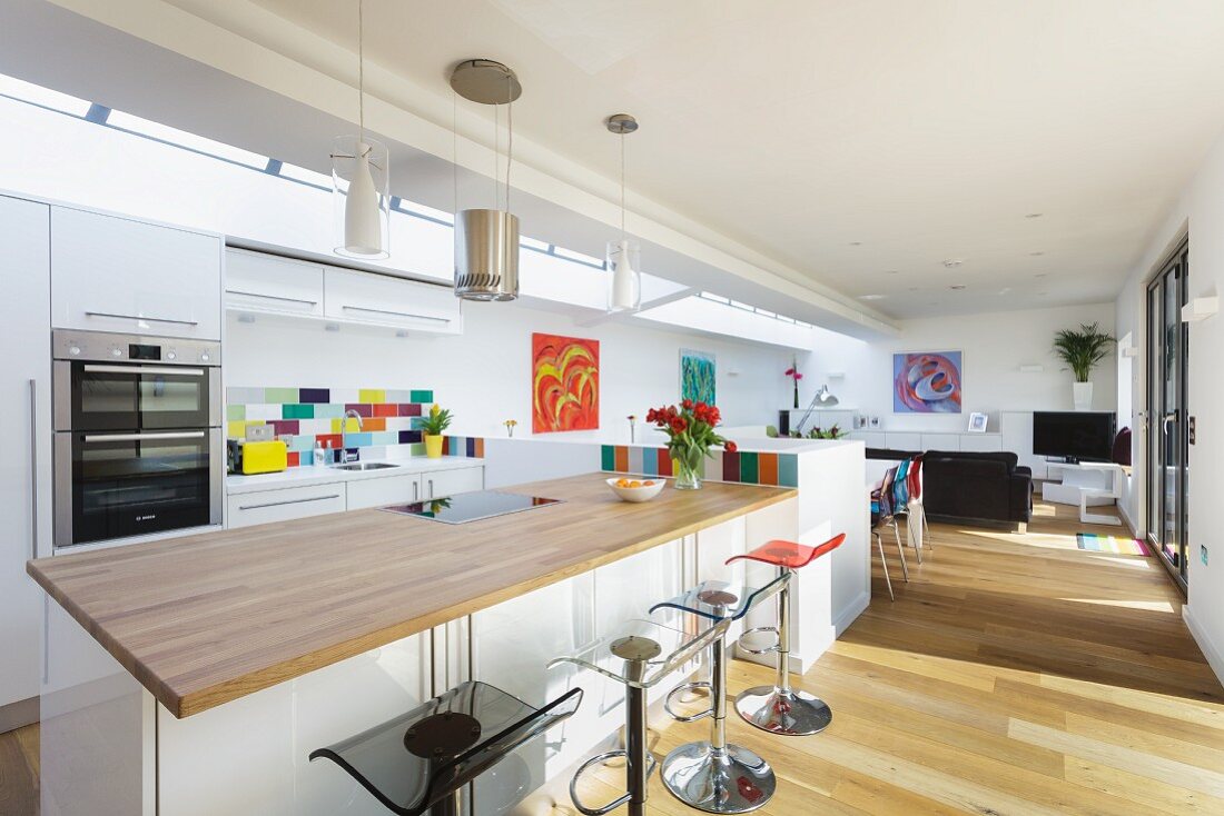Küchentheke mit hellem Holz als Arbeitsplatte und Barhockern in offenem Wohnraum