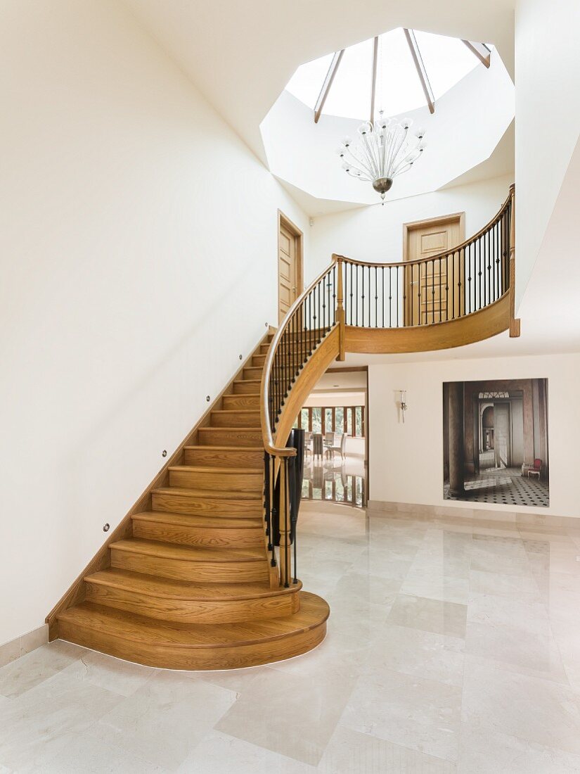 Skylight above curved wooden staircase in large foyer