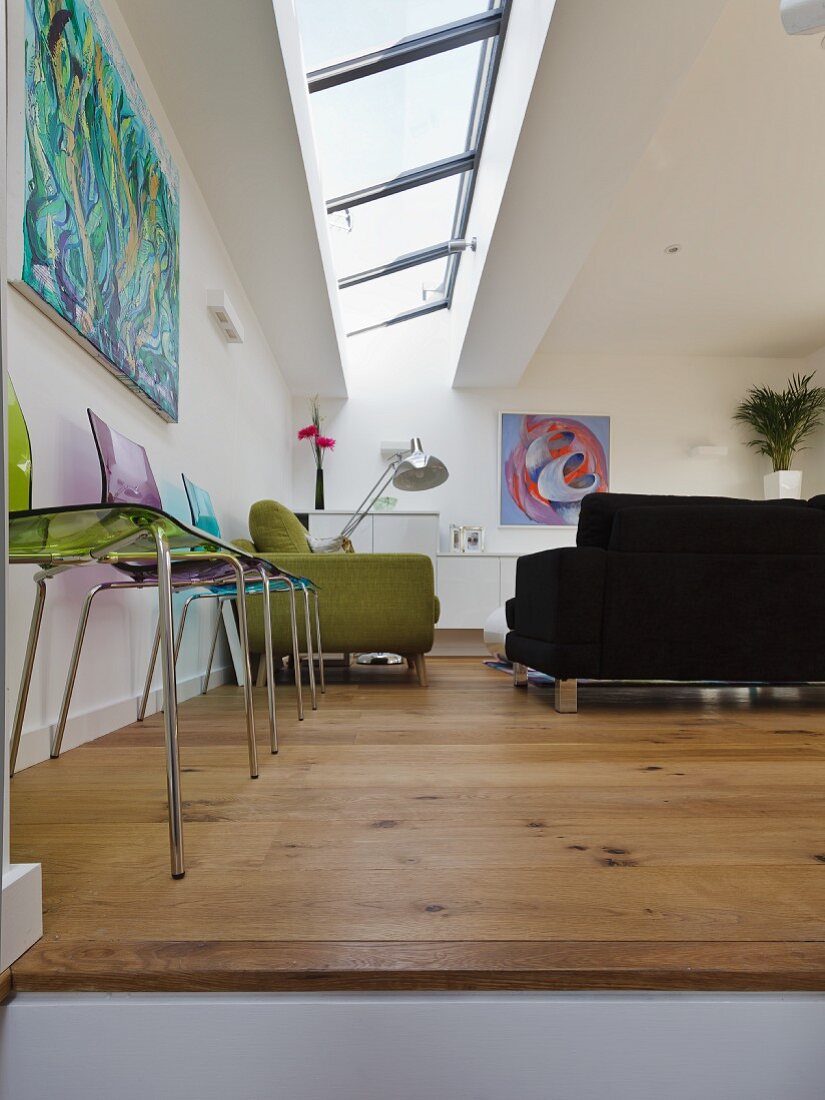 Colourful plastic chairs against wall and sofa set below skylights in living room
