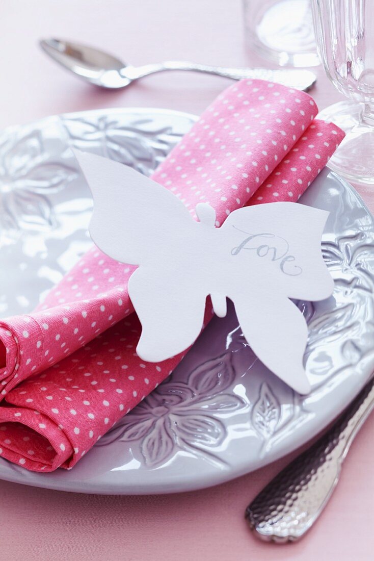 Place setting with napkin & 'Love' written on paper butterfly