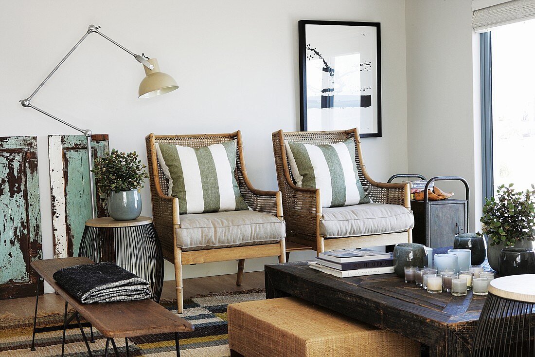 Rustic coffee table in front of armchairs with scatter cushions next to vintage standard lamp in modern setting