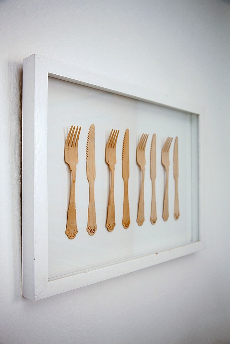 Gerahmtes Kunstobjekt mit aufgereihten Gabeln und Messern aus Holz