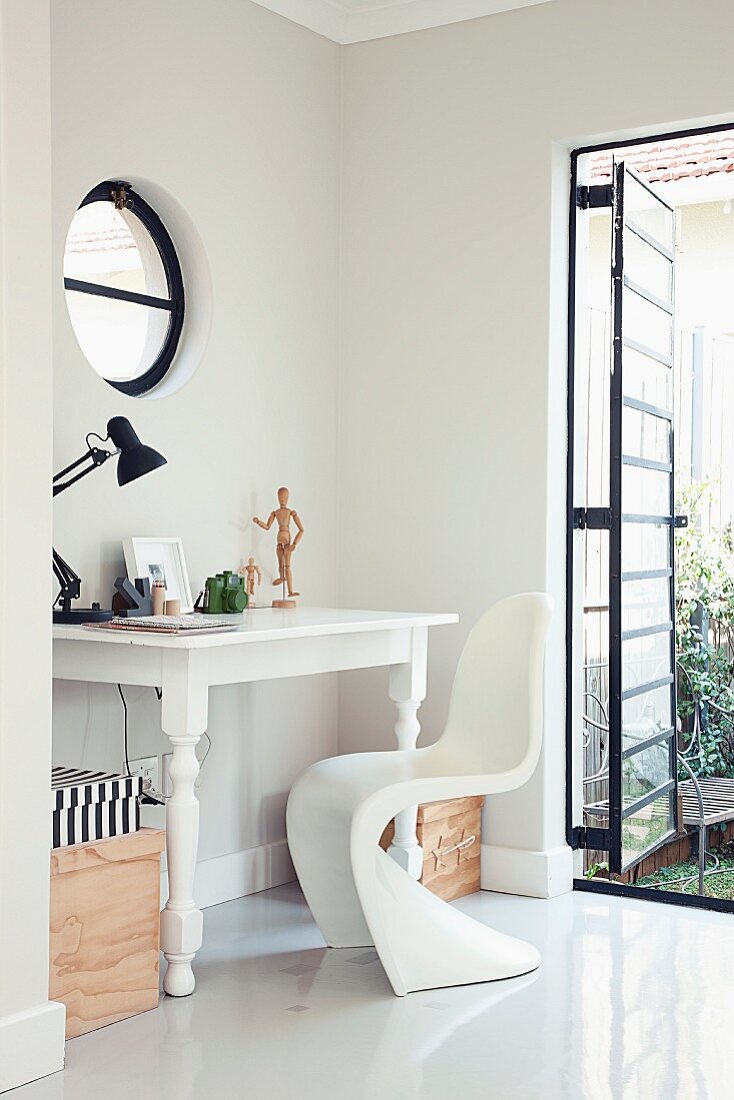 Weisser Antiktisch und Panton Chair in Zimmerecke mit metallgerahmter Industriefenstertür