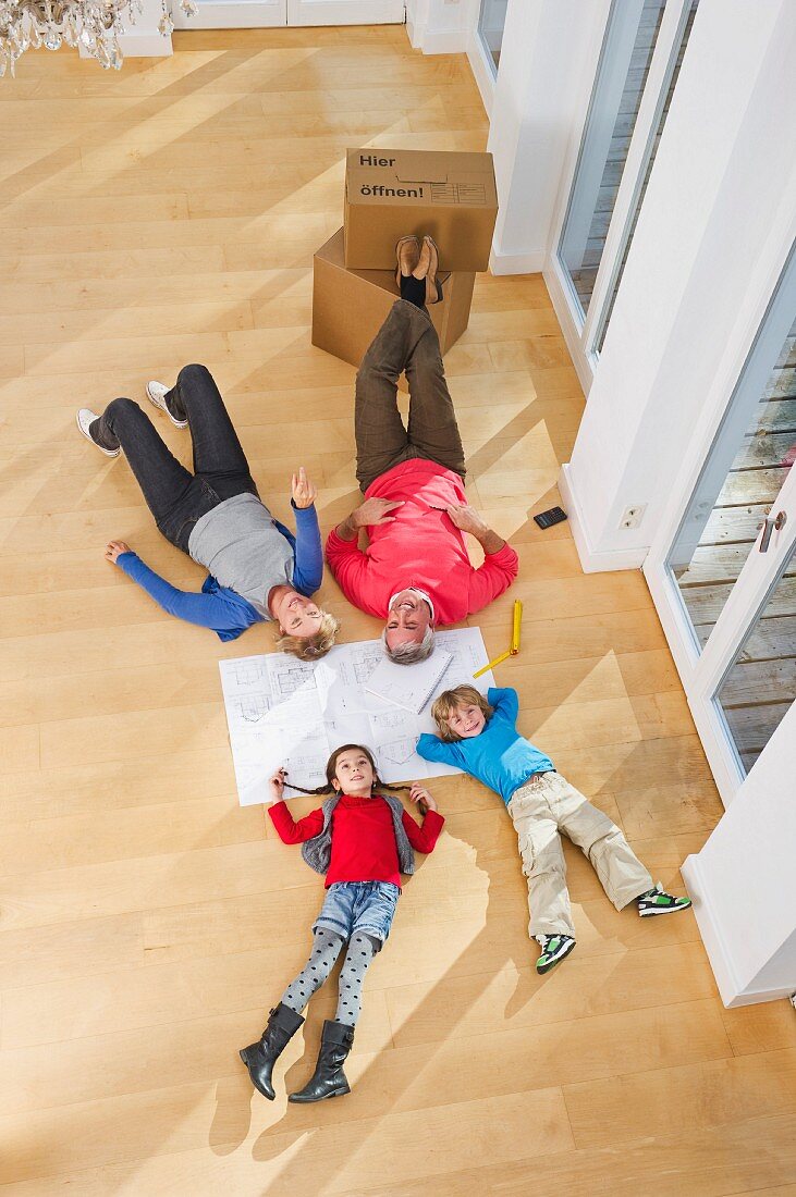 Family lying on floor of empty living room