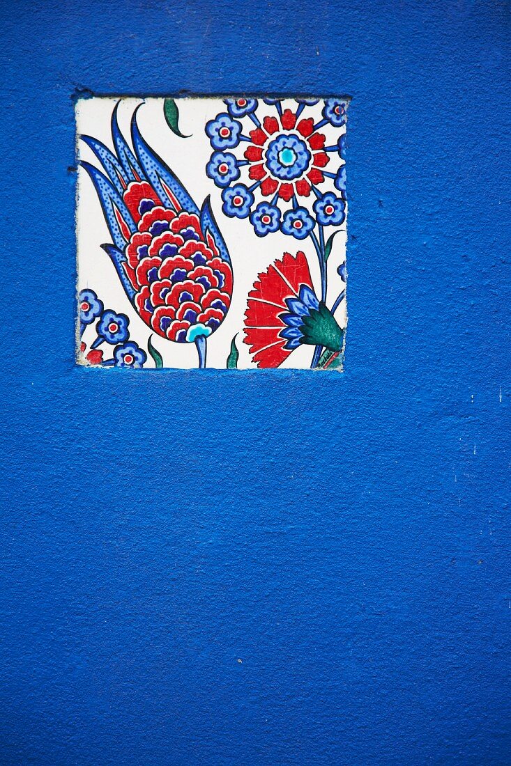Mosaikfliese mit Blumenmuster in einer blauen Wand
