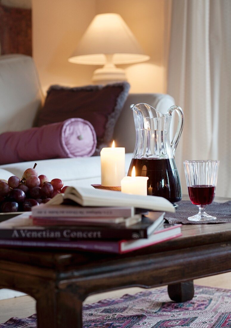 Books, grapes, candles and red wine on coffee table