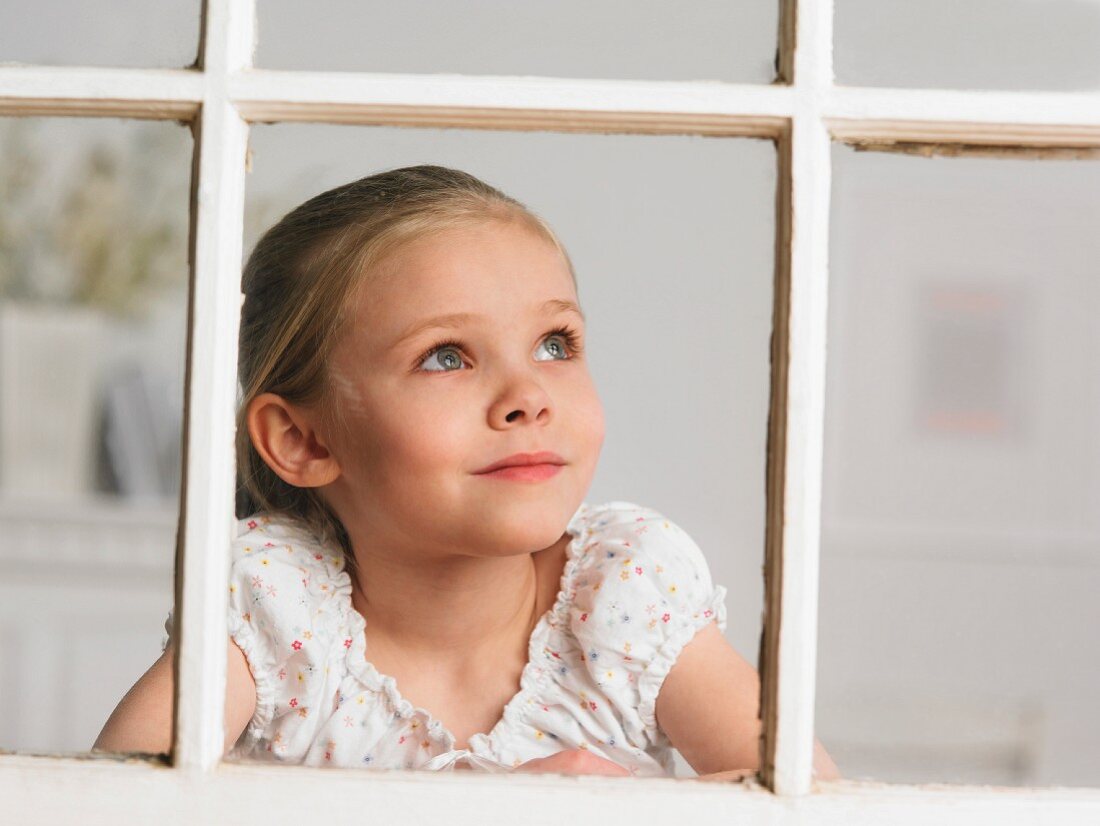 Junges Mädchen schaut aus Fenster