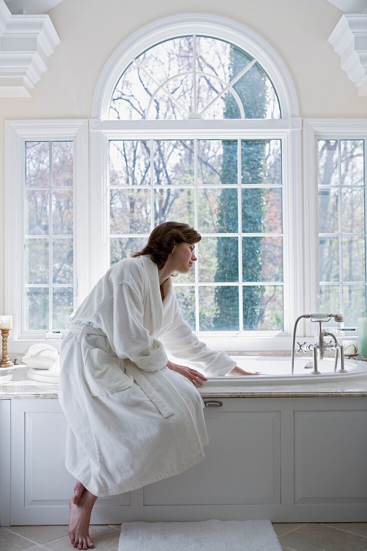 Woman in robe drawing bath