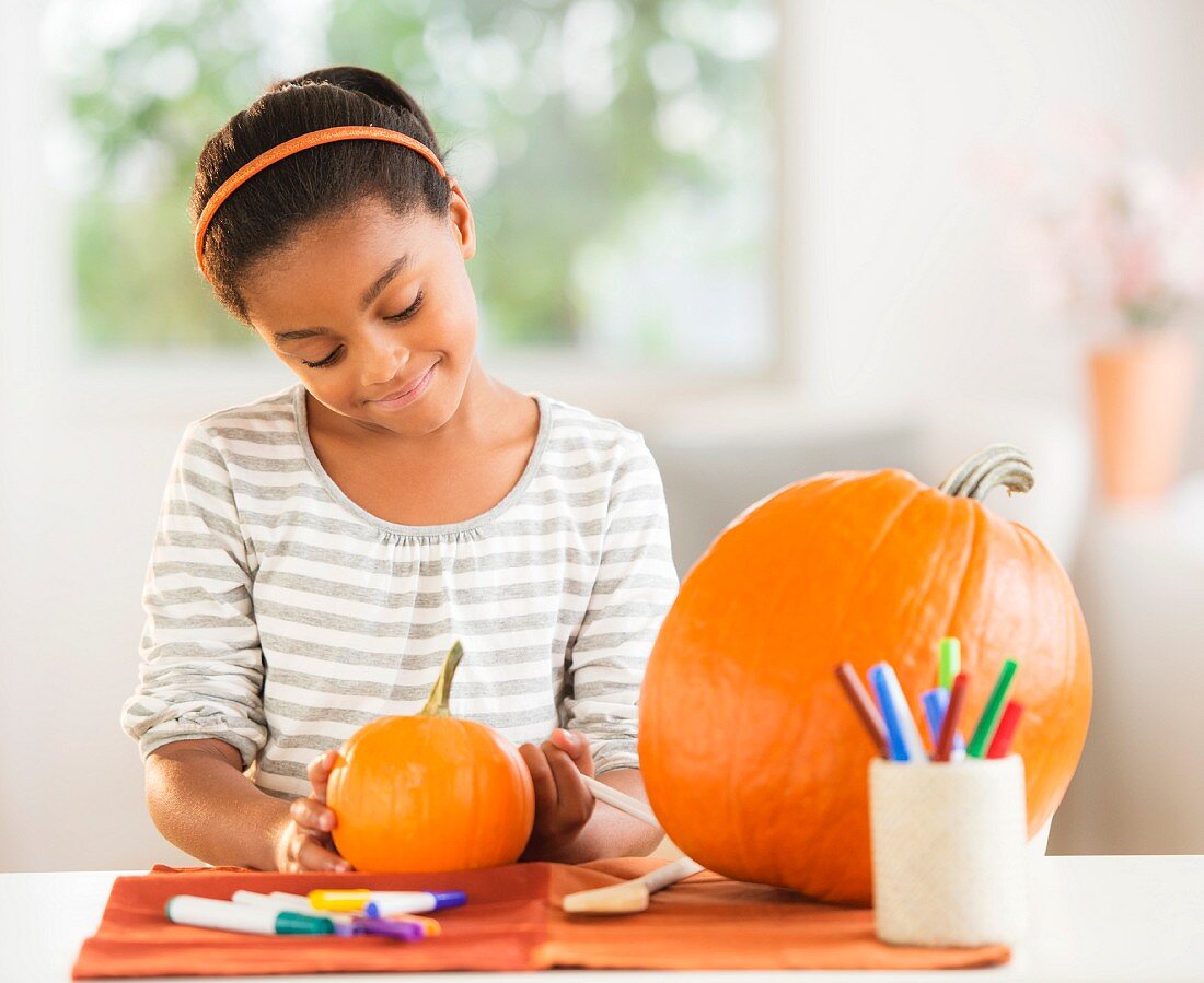 A girl decorating a Halloween pumpkin