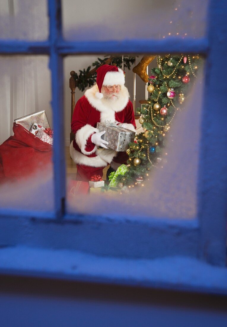 Santa Claus leaving gifts under Christmas tree