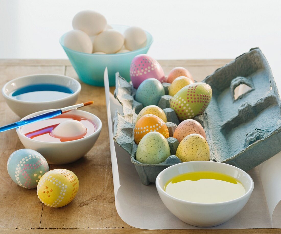 Verzierte Eier neben Schalen mit Ostereierfarbe