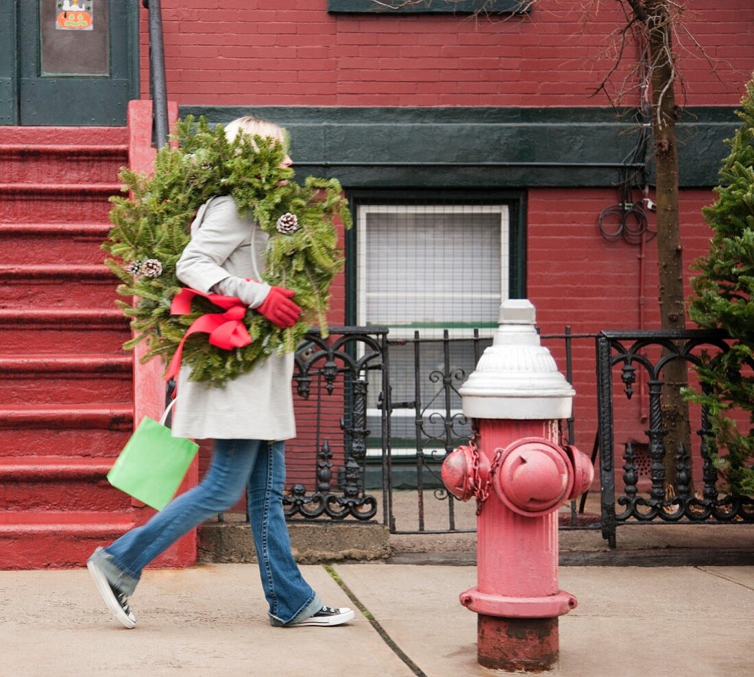 Woman carrying Christmas wreath on urban street