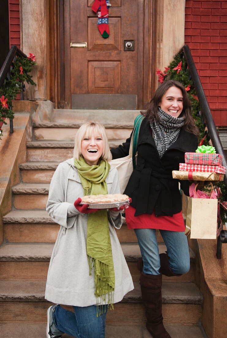 Zwei Frauen verlassen das Haus mit Weihnachtsgeschenken und Kuchen