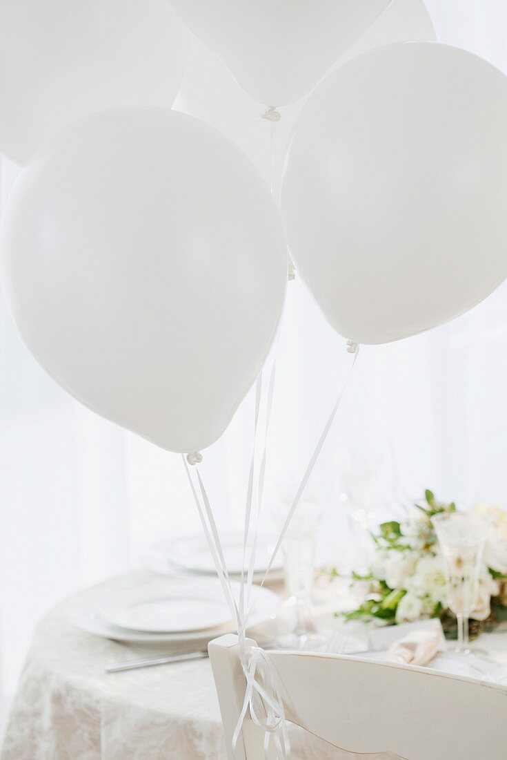 Weiß gedeckter Hochzeitstisch mit weissen Luftballons