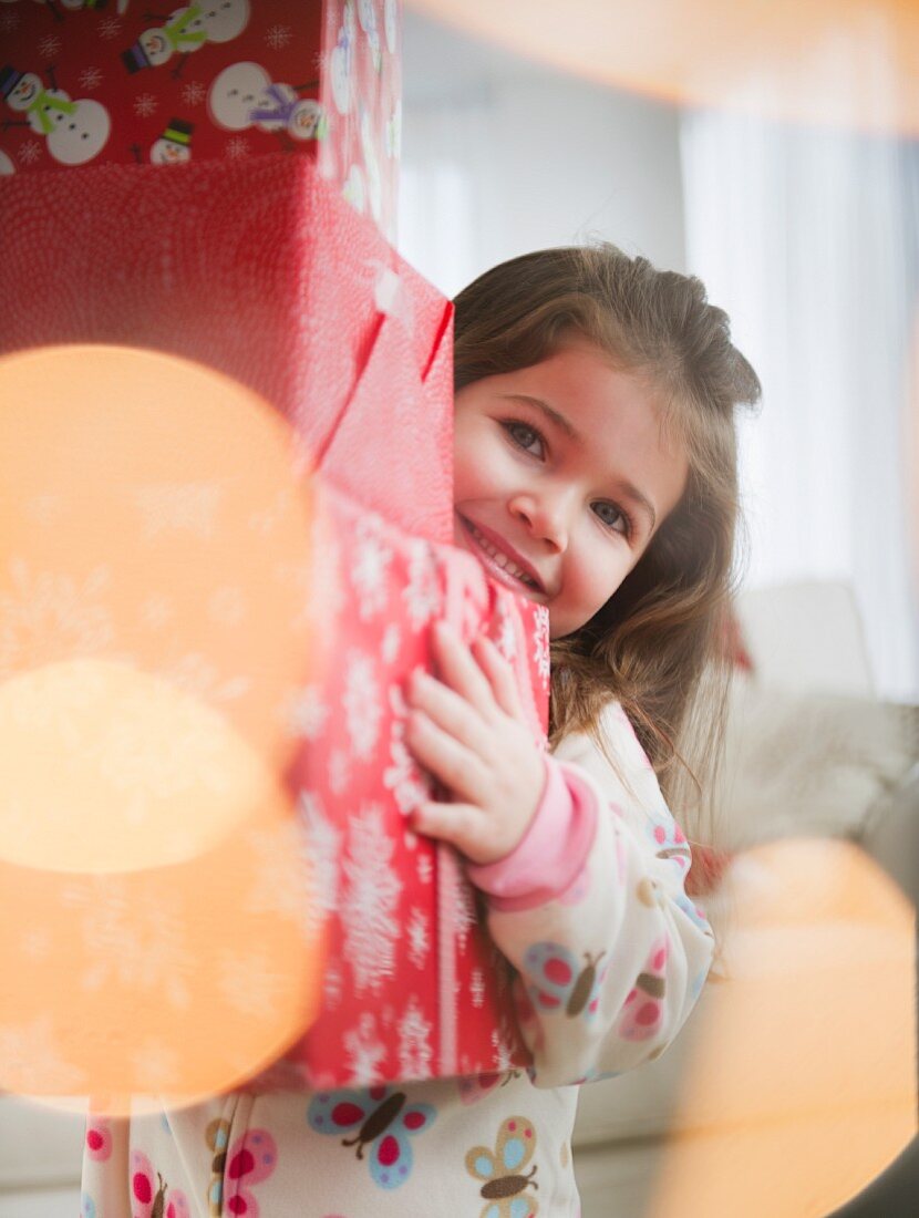 Kleines Mädchen trägt Stapel mit Weihnachtsgeschenken