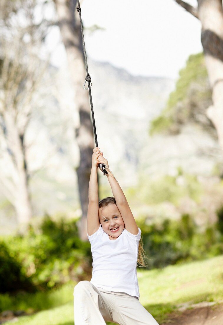 Girl (10-11) swinging on rope