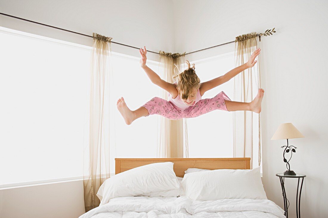 Blondes Mädchen springt auf dem Bett