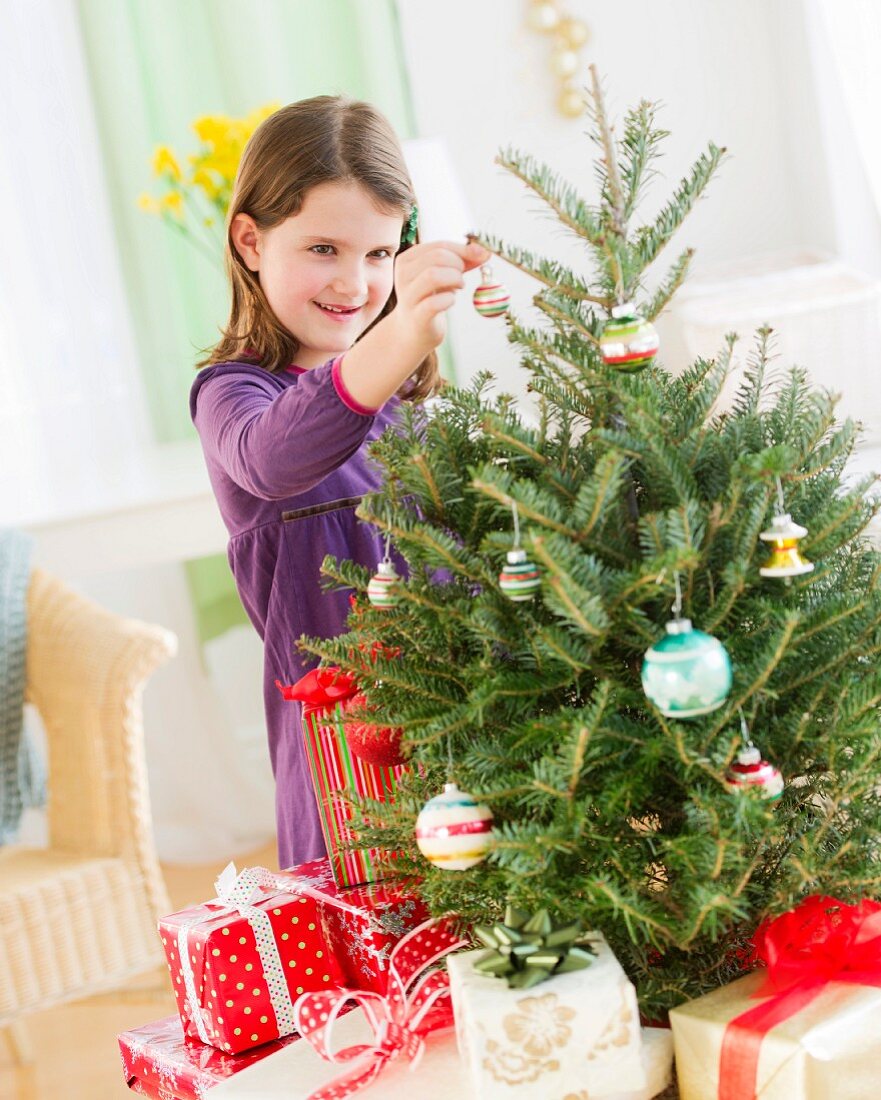 Mädchen schmückt den Weihnachtsbaum