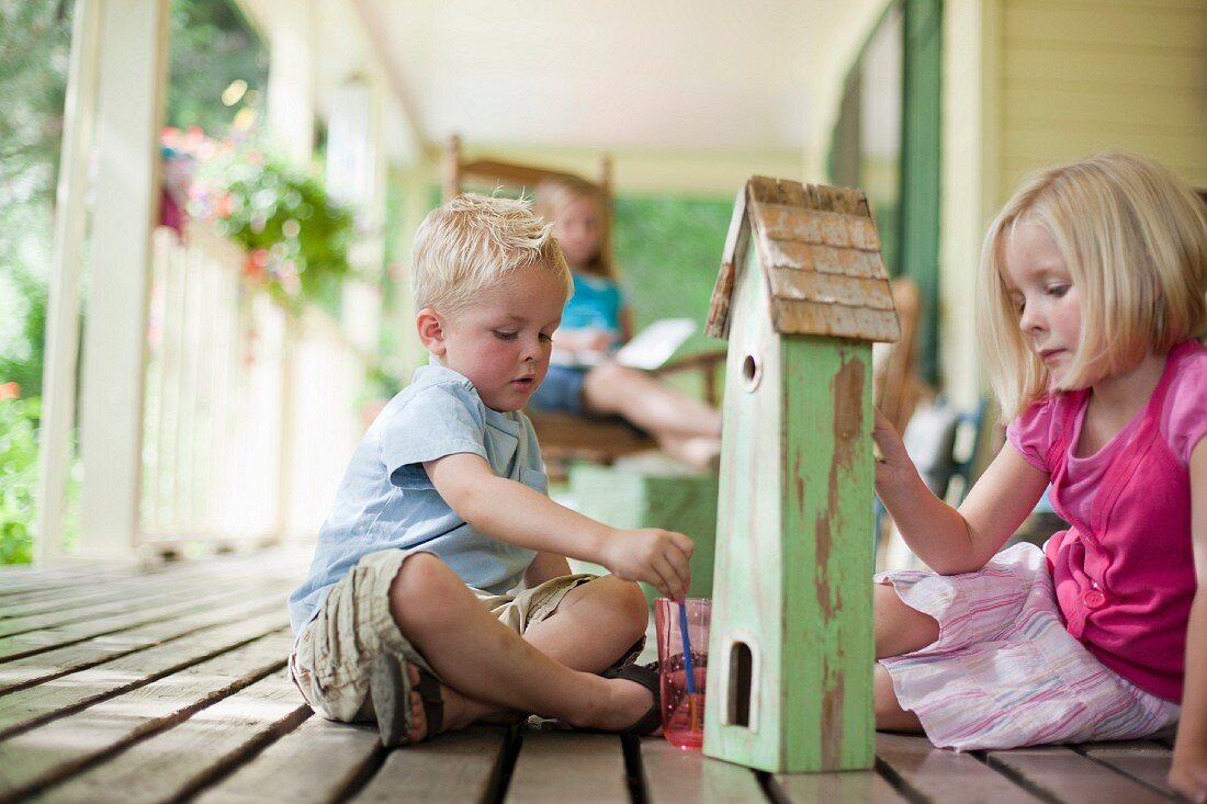 Brother and sister painting birdhouse together