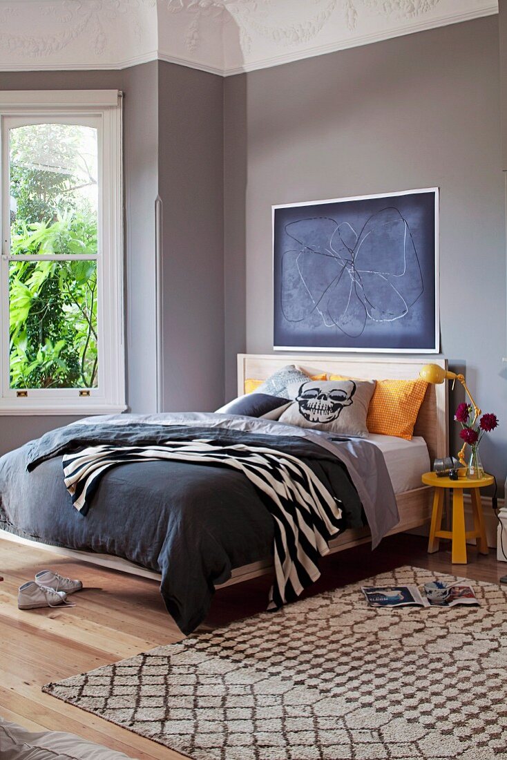 Doppelbett mit dunkelgrauem Bezug und Totenkopf Illustration unter anthrazitfarbenem Kunstplakat