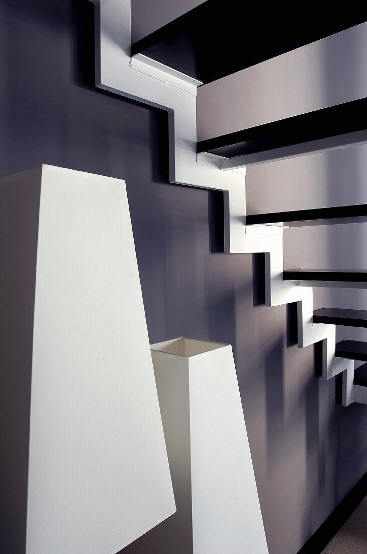 White lampshades below staircase against black-painted wall