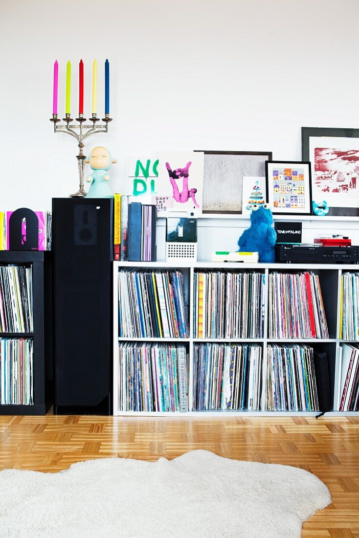 Record collection on shelves against wall & candelabra on speaker