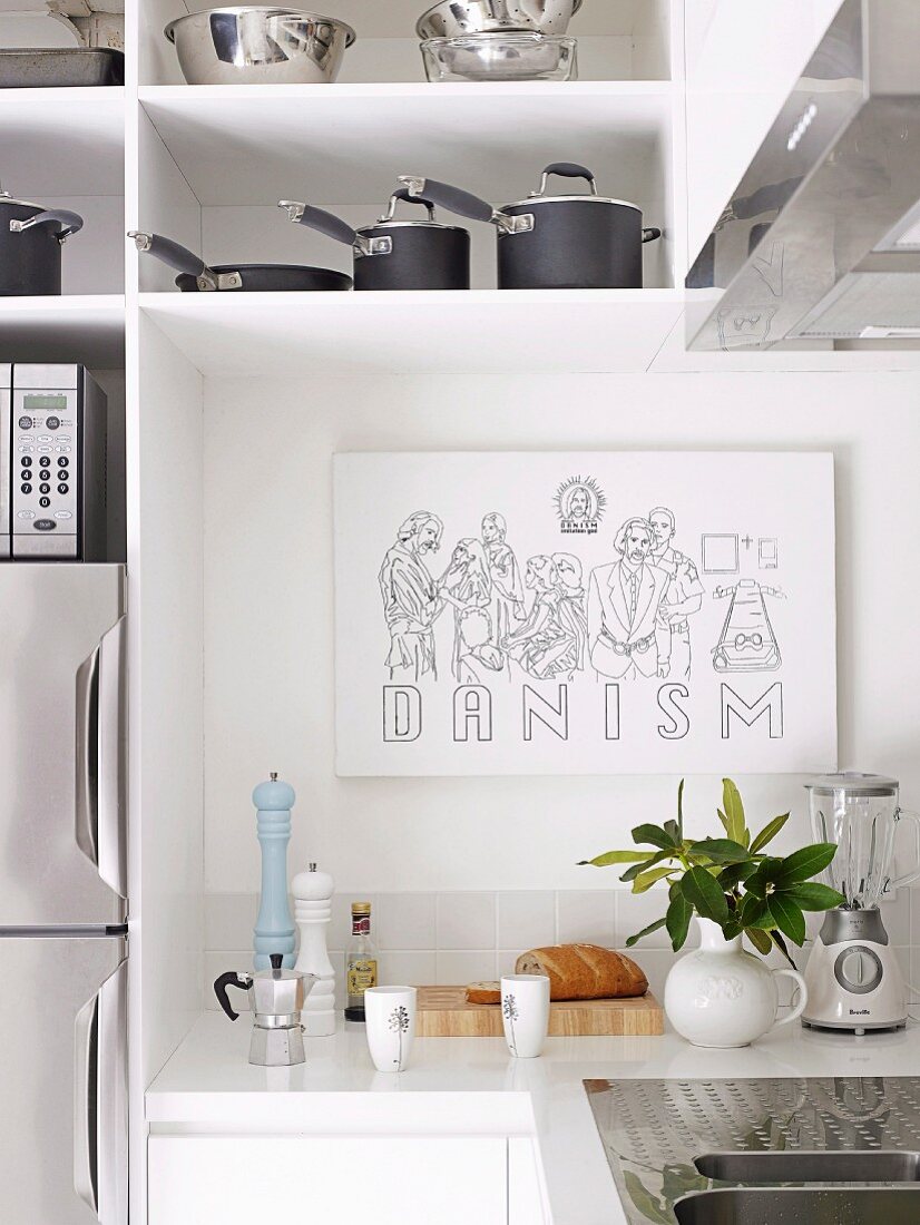 Drawing on wall of white fitted kitchen with stainless steel pots and pans