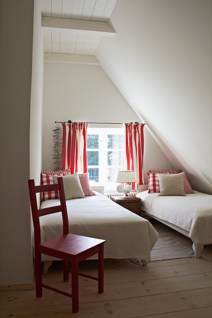 Kleines Gästeschlafzimmer unterm Dach in schlichtem Weiß mit roten Farbakzenten