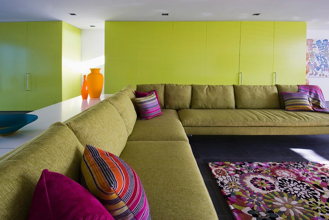 Yellow cupboard doors and purple accents in minimalist living room with enormous corner couch