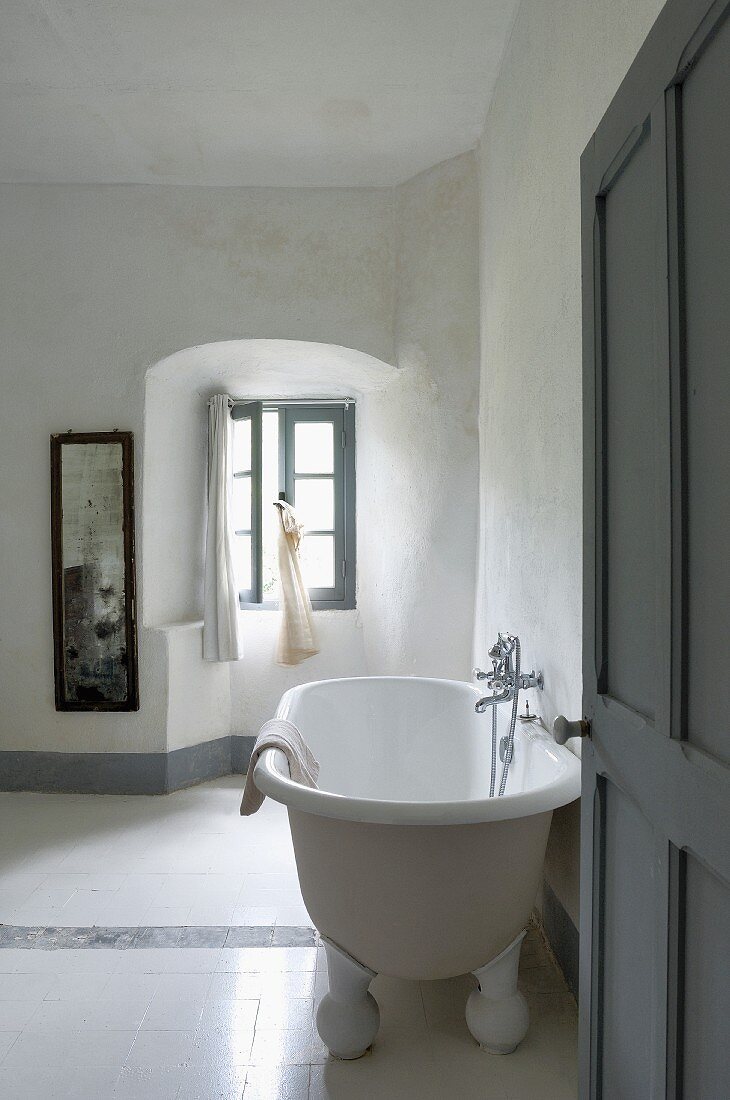 Einfaches Badezimmer mit antiker Badewanne und weissen Bodenfliesen