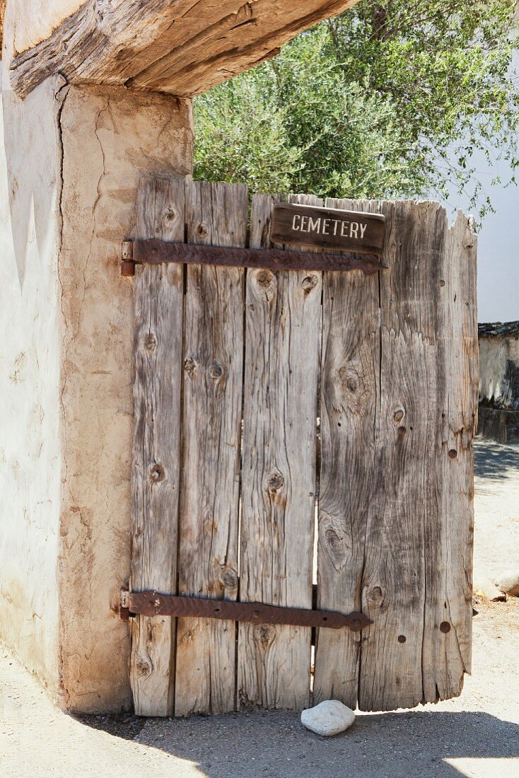 Old wooden cemetery gate in the adobe wall at Mission San Miguel Archangel in San Miguel