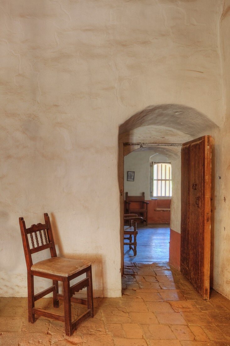 Empty chair gaurds interior doorway of adobe building, Mission La Purisima State Historic Park, Lompoc, California