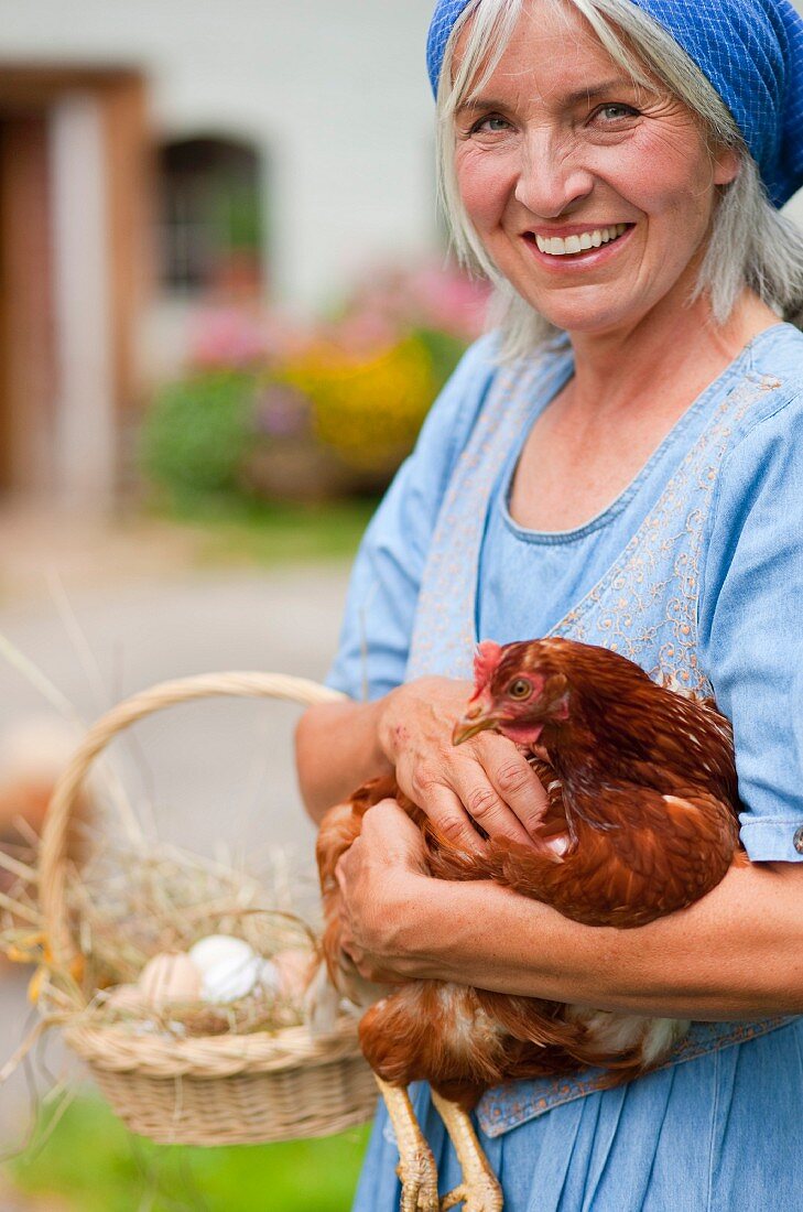 Germany, Bavaria, Mature woman with basket of fresh eggs and chicken